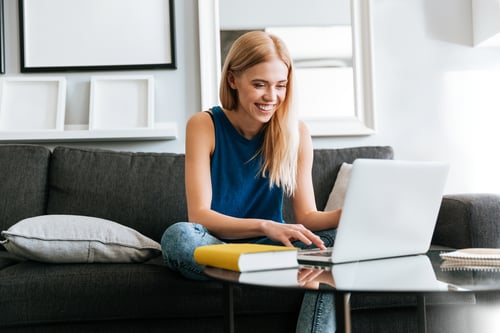happy-woman-sitting-sofa-using-laptop-home